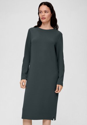 Langärmliges Kleid aus dunkelgrünem, strukturiertem Stoff, gerader Schnitt, knielang mit seitlichen Schlitzern. Minimalistisches Design und runder Ausschnitt.