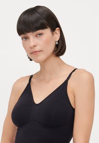 Black camisole with thin adjustable straps, featuring a V-neck design and textured detailing on the bust area. Smooth fabric.