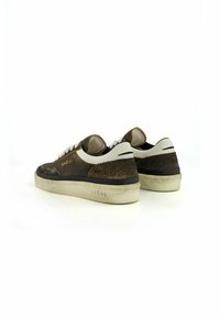 Sneakers in suede marrone con lacci e dettagli sul tallone bianchi. Presentano una tomaia testurizzata e una suola in gomma bianca. Il marchio è visibile sul lato.