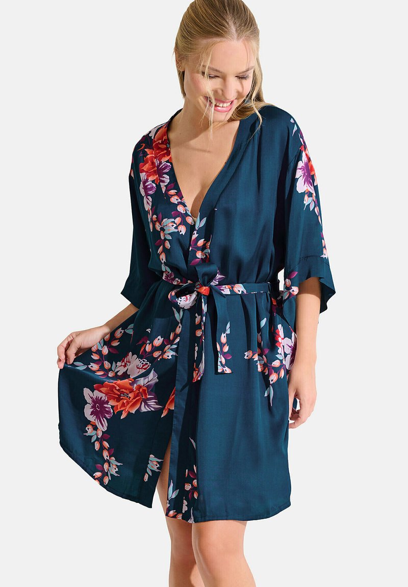 Kimono fleuri en bleu sarcelle avec un décolleté en V et des manches 3/4. Présente des motifs floraux vibrants dans des tons de violet et d'orange, ceinturé à la taille.