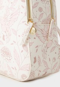 Zaino con pattern floreale in crema con accenti rosa. Materiale resistente, accessori in oro e dettaglio con zip laterale. Finitura testurizzata.
