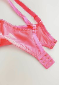 Pink satin bra featuring adjustable straps, a hook-and-eye closure with gold hardware, and delicate scalloped edges along the seams.