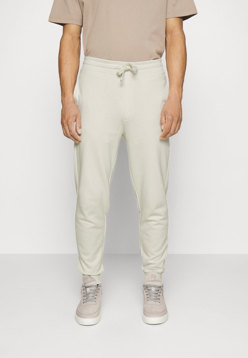 Ljust beige joggers i mjukt tyg, med en elastisk midja med dragsko, tapered ben och subtila sidfickor.