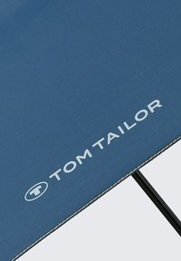 Blauwe parasol met het "TOM TAILOR" logo in het wit, met een stevige zwarte metalen frame en contrasterende witte stiksels langs de rand.