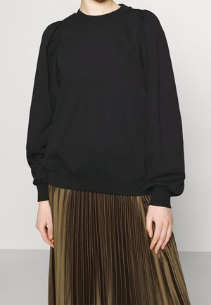 Sudadera negra con mangas abullonadas, cuello y puños de canalé, combinada con una falda acampanada de color verde oliva, diseño simple y moderno.