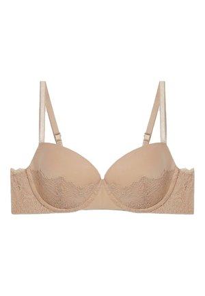Soutien-gorge beige avec des coques rembourrées, dentelle le long de la bande, bretelles réglables et une finition lisse. Présente une texture douce et des détails de design subtils.