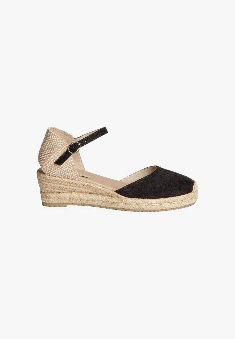 Espadrille de cuña de ante negro con un tacón trenzado de color marrón claro. Presenta una correa de tobillo negra con un hebilla circular y una plantilla beige suave.