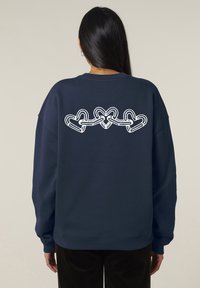 Felpa navy con maniche lunghe, caratterizzata da un design a catena di cuori bianchi ricamato sulla schiena. Tessuto morbido e vestibilità comoda.