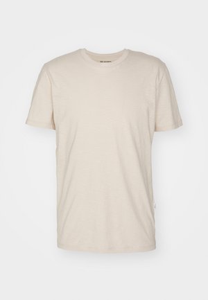 Bež majica s kratkimi rokavi iz mehkega materiala, z okroglo izrezom, ravnim krojem in minimalnim znamčenjem na vratu.