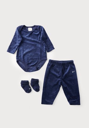 Ensemble pour bébé en velours bleu marine comprenant un bodysuit à manches longues, un pantalon assorti et des chaussettes avec des accents de logo. Texture douce partout.