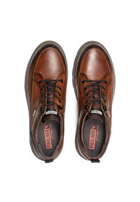 Zapatos de cuero marrón con cordones negros, punta redonda, cuello acolchado y suela de goma texturizada. Logo visible en la lengüeta y en el lateral.