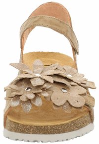 Beżowe sandały na koturnie z kwiatowymi aplikacjami, teksturowanymi paskami oraz wyściełaną wkładką. Biała gumowa podeszwa z wzorzystym korkiem.