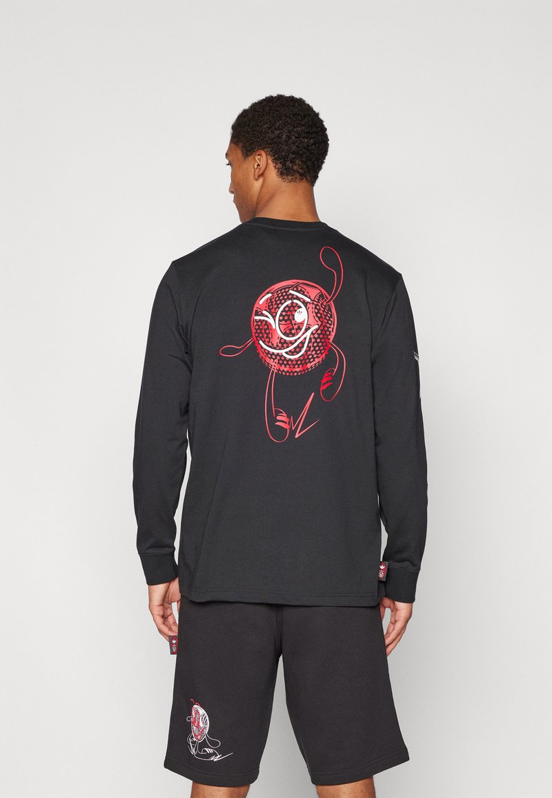 Long-sleeve black shirt featuring a red graphic design, paired with black shorts that have a similar red accent, both made of soft fabric.