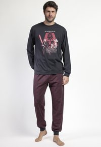 Camisa de pijama de manga larga negra con un gr�áfico rojo de "Star Wars"; pantalones de pijama rojos con un diseño estampado y puños elásticos. Tejido suave, ajuste relajado.