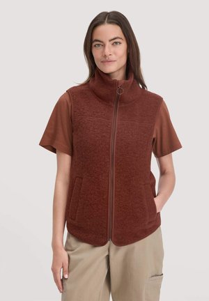 Brown fleece vest with high collar, featuring a front zipper and two side pockets, worn over a short-sleeve brown shirt.