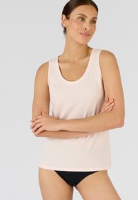 Canotta rosa chiaro con scollatura a barca, caratterizzata da un bordo ondulato. Realizzata in materiale morbido, ha una vestibilità comoda ed è abbinata a mutandine nere.