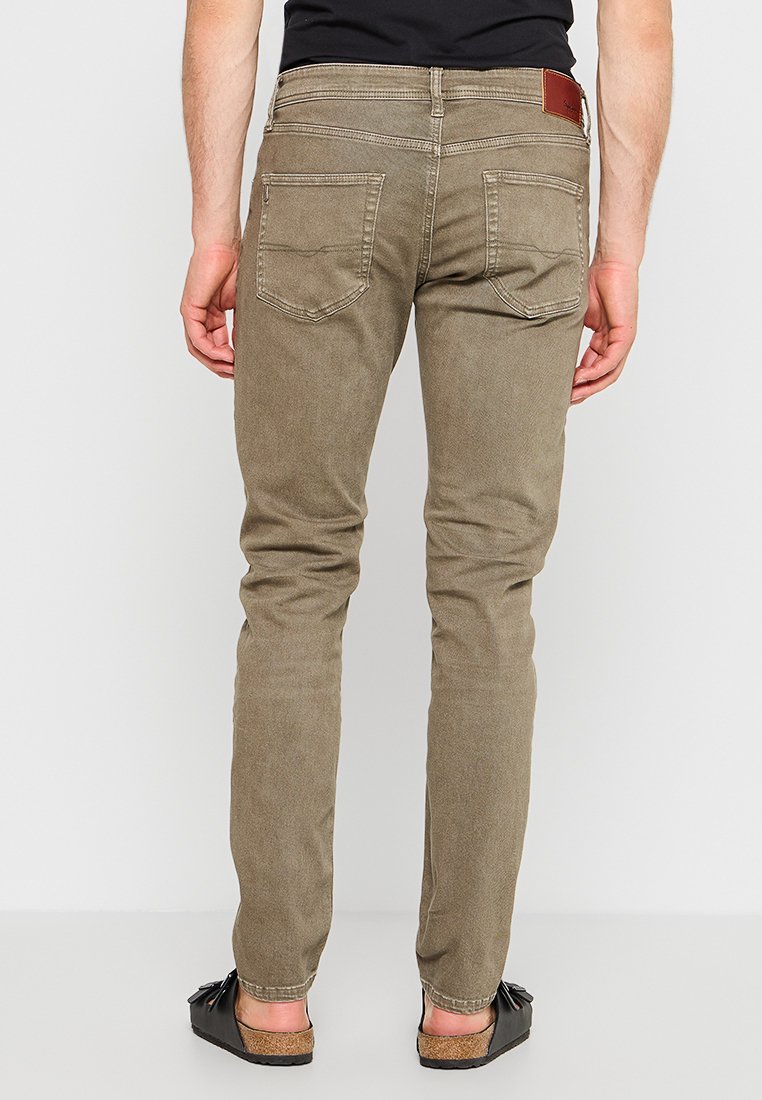 Jeans ajustados color caqui con una textura suave, que cuentan con bolsillos traseros y una etiqueta de cuero marrón en la cinturilla. Terminados con un dobladillo limpio.