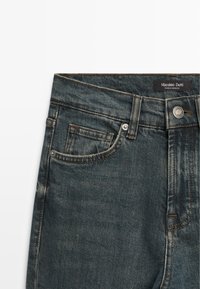 Dark blue denim jeans with a classic design. Features a front pocket, contrasting stitching, and a tag labeled "Massimo Dutti."