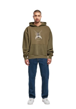 Olivengrønn hettegenser med grafisk trykk på forsiden, kombinert med blå jeans og hvite sneakers. Har en frontlomme og justerbar hette.