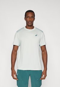 Αθλητικό T-shirt ανοιχτού γκρι χρώματος με κοντά μανίκια, με στρογγυλή λαιμόκοψη και μικρό λογότυπο στο στήθος. Λείο ύφασμα με κανονική εφαρμογή.