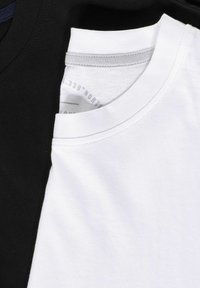 Twee T-shirts op elkaar gestapeld, één zwart en één wit. Beide hebben een ronde halslijn en een zachte katoenen textuur. Grijze stikdetails zijn zichtbaar.