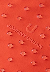 Orangefarbener Stoff mit Wassertröpfchen, die auf der Oberfläche abperlen, und eingeprägtem Text "JOHNNY URBAN" mit einem stilisierten J-Logo.