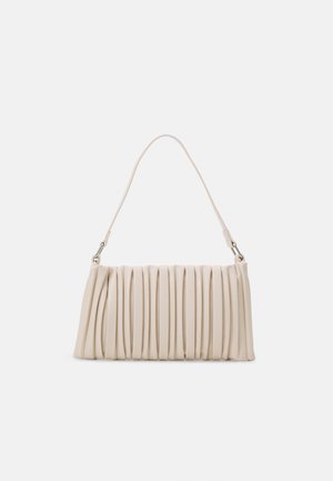 Beige pleatattu käsilaukku, jossa on yksi olkahihna ja hopeanväriset metalliklipsit valkoista taustaa vasten.