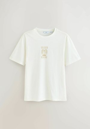 Cremfarbener Baumwoll-T-Shirt mit kurzen Ärmeln, das ein goldenes Grafikdesign mit der Aufschrift "GOLDEN REVERIE" und einem Regenbogenmotiv auf der Vorderseite zeigt.