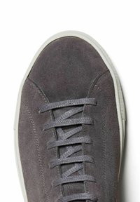 Graue Wildledersneaker mit runder Zehenpartie, weißer Gummisohle und passenden grauen Schnürsenkeln. Glatte Textur mit minimalen Nähten an der Seite.
