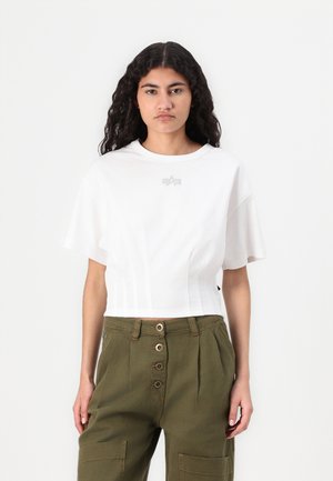 T-shirt blanc court à manches courtes, avec un design en relief subtil sur la poitrine. Assorti avec un pantalon taille haute vert olive.