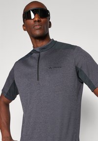 Camisa atlética de manga curta, cinza escuro, com gola de meio fecho, apresentando pain�éis de ombro em verde escuro contrastante e um pequeno logotipo no peito.