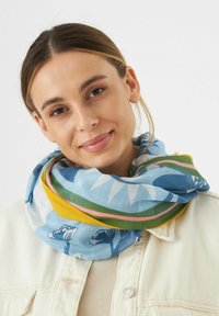 Écharpe multicolore avec des motifs bleus, verts, jaunes et roses, fabriquée en tissu léger, enroulée autour du cou.