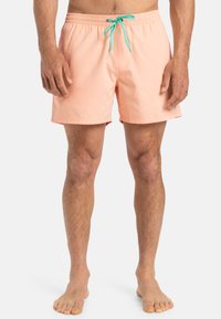 Shorts de bain pêche avec une ceinture élastique et un cordon turquoise. Longueur au-dessus du genou avec un tissu lisse et des poches latérales.