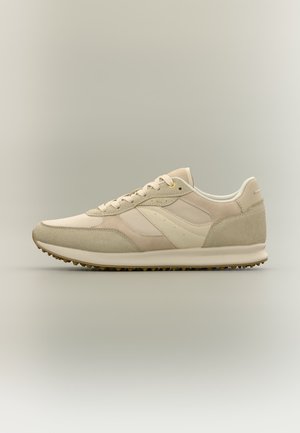 Baskets basses beige et crème avec des accents en daim, des panneaux en mesh, une fermeture à lacets, et une semelle en caoutchouc texturée.