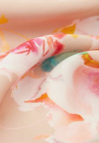 Bloemige stof in zachte roze tinten met aquarelachtige patronen. Glad van textuur met levendige accenten van rood, geel en blauw.