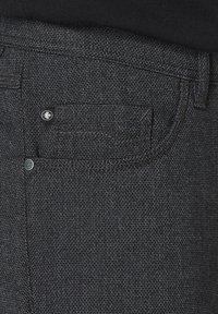 Black denim jeans featuring a textured fabric, with a back pocket detail and a small logo tag near the pocket.