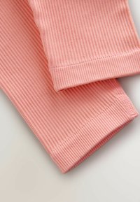 Leggings rosa chiaro a coste con una texture liscia, cuciture ordinate e design con caviglia rastremata.