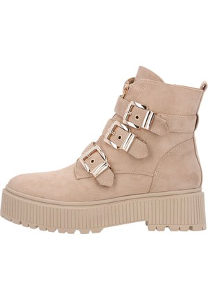 Bottines en fausse suede beige avec trois sangles à boucle réglables, fermeture éclair latérale et semelle épaisse à nervures. Détail de surface texturée.