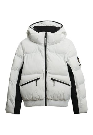 Witte en zwarte pufferjack met een capuchon, ritszakken, een gewatteerde textuur en een geribbelde zoom. Geaccentueerd met branding op de capuchon.