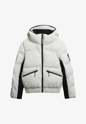 Puffjakke i hvid og sort, med hætte, lynlåslommer, quiltet tekstur og ribbestrikket kant. Fremhævet med branding på hætten.