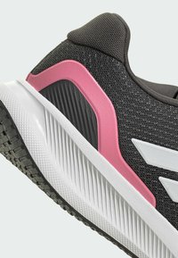 Czarny but sportowy z szarą siateczkową cholewką, różowymi i szarymi akcentami oraz białą środkową podeszwą z fakturowaną gumową podeszwą zapewniającą przyczepność.