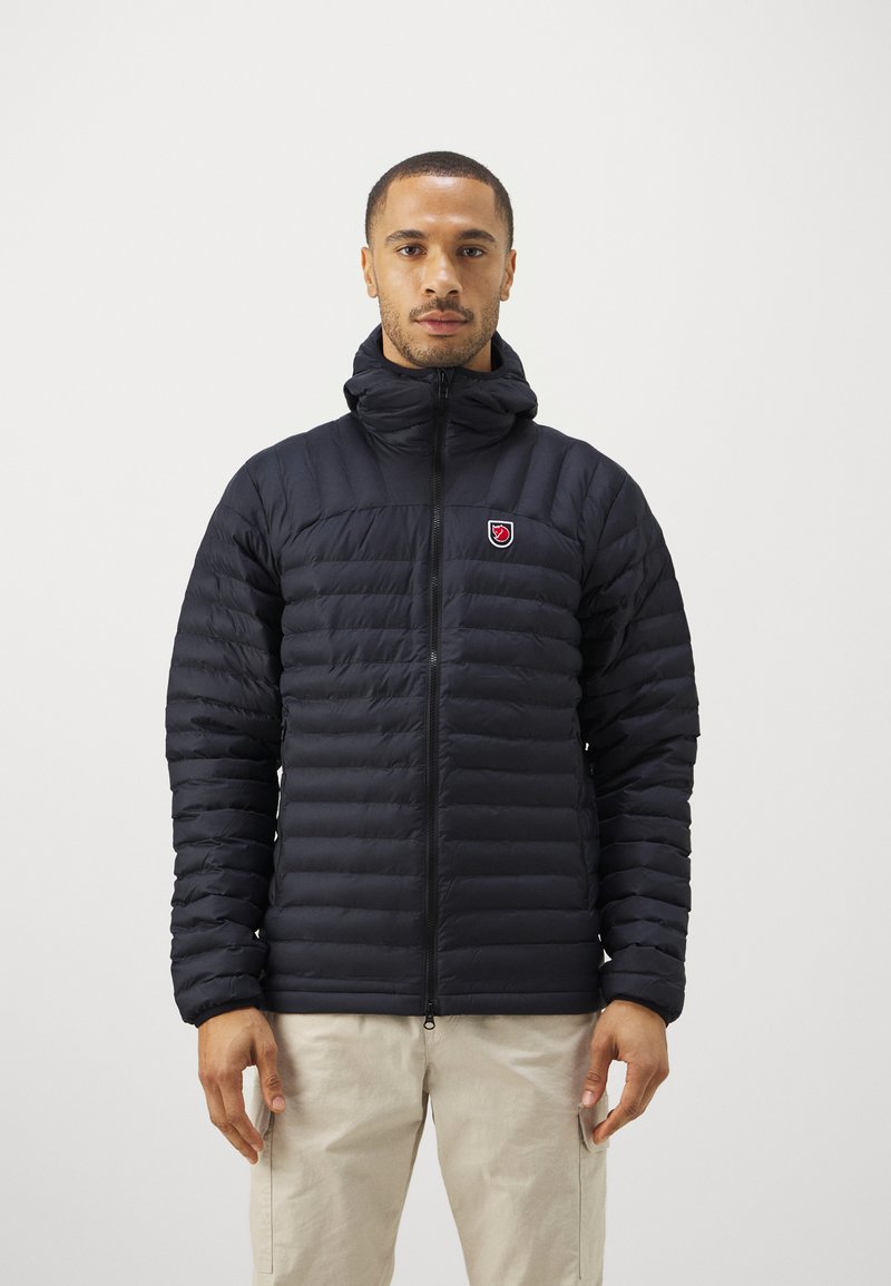 Fekete puffertakó cipzárral elöl, magas gallérral és steppelt textúrával. A mellkason egy kis logó címer található.