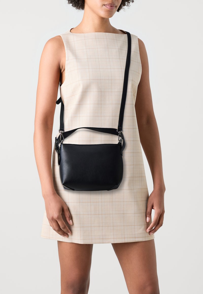 Borsa a tracolla in pelle nera, con forma rettangolare, tracolla staccabile e accessori in argento; texture liscia e design minimalista.