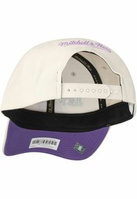 Cream baseball cap with a purple visor. Features "Mitchell & Ness" embroidered in lavender on the front and a black inner lining.