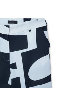 Gestreifte Hose in Marineblau und Hellblau mit großen grafischen Designs. Aus glattem Material mit tailliertem Bund. Markenetikett sichtbar.