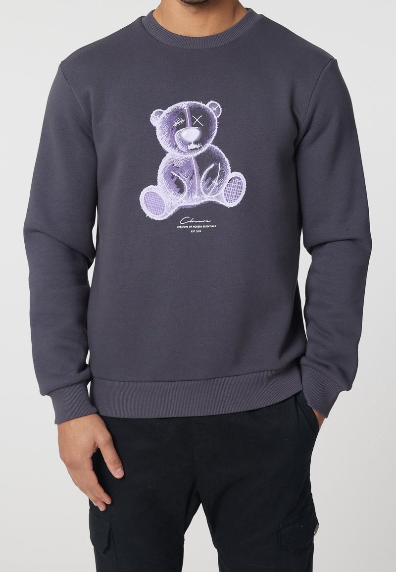Felpa grigia con grafica di un orso stilizzato sul davanti. Polsini e orlo a coste, texture morbida, vestibilità casual e maniche lunghe.