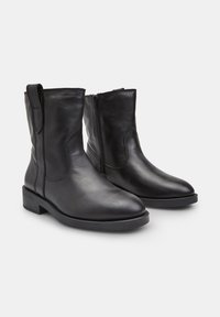 Melnas ādas potīšu zābaki ar elegantu dizainu, aprīkoti ar sānu rāvējslēdzēju, noapaļotu purngalu un zemu blokveida papēdi. Vienmērīga tekstūra ar minimāliem akcentiem.