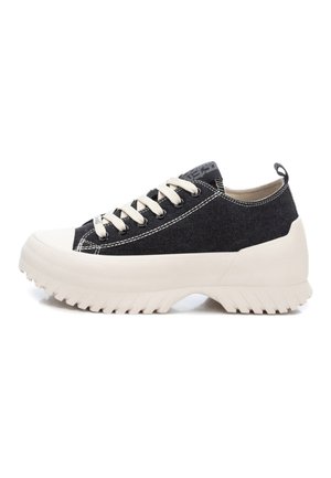 Zapatillas de lona negras con una suela de goma beige gruesa, que cuentan con cordones crema y costuras en contraste. Incluyen una pestaña de agarre en el talón.