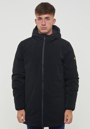 Parka nera imbottita con cappuccio, zip frontale eTaspringo. Dotata di un distintivo logo giallo sulla manica sinistra. Texture liscia.