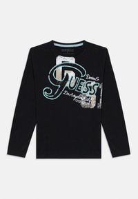 Svart langermet t-skjorte laget av bomull, med et grafisk "GUESS"-logo i blått og hvitt med slitte detaljer.